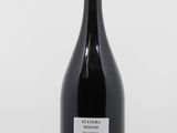 a bottle of red wine sitting on top of a white table