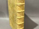 an old yellow book sitting on top of a table next to a gray wall