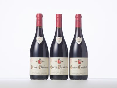 three bottles of red wine are lined up on a table
