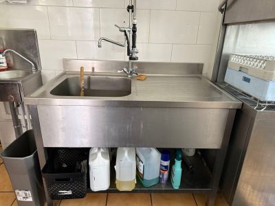 un évier en inox dans une cuisine, avec une poubelle placée en dessous
