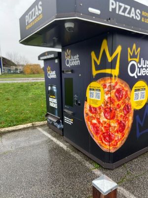 une boîte à pizza ornée d'une couronne, posée sur un parking