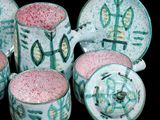 five cups and a teapot sitting on a table