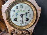 a clock that is sitting on a table with a statue in the background