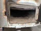 a dirty oven with a metal door on the side of it