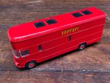 un petit bus rouge posé sur une table en bois