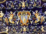 a blue and gold vase with angels and cherries on it