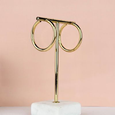 une paire de boucles d'oreilles créoles en or posées sur un socle en marbre