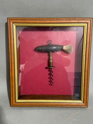 une photo encadrée représentant un décapsuleur dans lequel est inséré un tire-bouchon
