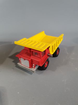 yellow and red toy dump truck sitting next to each other on a gray surface