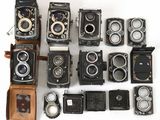 Plusieurs anciens appareils photo sont alignés sur une surface blanche