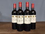 three bottles of red wine are lined up on a wooden table