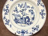 une image représentant une assiette bleue et blanche sur laquelle figure l'image d'un homme dans un bateau