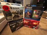Trois boîtes de cartes « Magic : The Gathering » sont posées sur une table