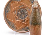 a small vase next to a plate with a design on it