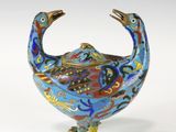 un objet en forme d'oiseau bleu et rouge sur une surface blanche