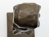 a sculpture of a rock sitting on top of a piece of metal