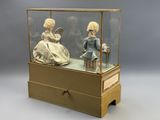 deux poupées dans une vitrine posée sur une table