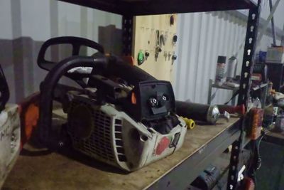 une tronçonneuse posée sur une étagère dans un garage