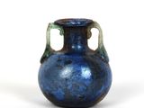 un vase bleu posé sur une surface blanche
