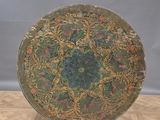 an old round metal tray on a wooden stand on a wooden floor