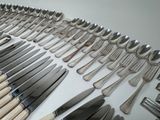 a lot of silverware on a table with knives and spoons