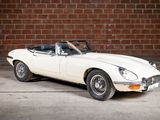 a white sports car parked in front of a brick wall
