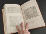 a hand that is holding a book open on a table
