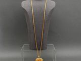 a gold necklace with a heart shaped pendant on a mannequin