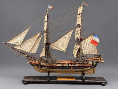 une vieille maquette en bois représentant un voilier arborant un drapeau