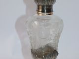 a glass bottle with a silver lid on a white surface