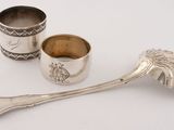 two silver spoons and a silver cup on a white surface