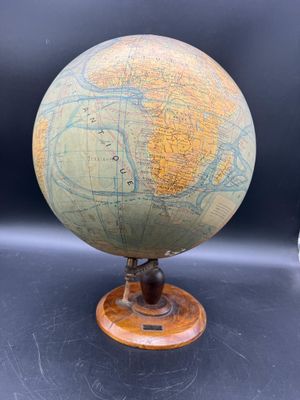 un vieux globe posé sur un socle en bois, lui-même posé sur une table