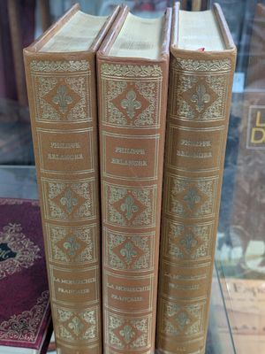 Trois vieux livres sont exposés dans une vitrine.