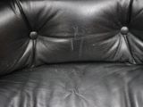 black leather chair with buttons on the back of it in a living room