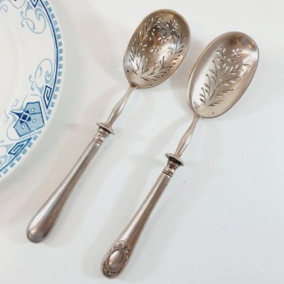 two silver spoons and a plate on a table