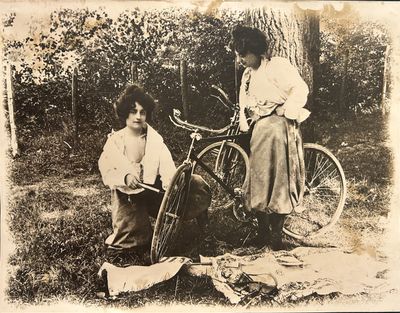 deux femmes debout à côté d'un vélo dans l'herbe