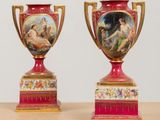 two red vases with paintings on them sitting on a table