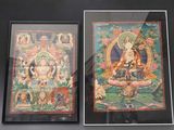 deux tableaux représentant des bouddhas, encadrés et exposés dans une vitrine