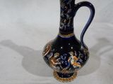 un vase bleu et or posé sur une surface blanche