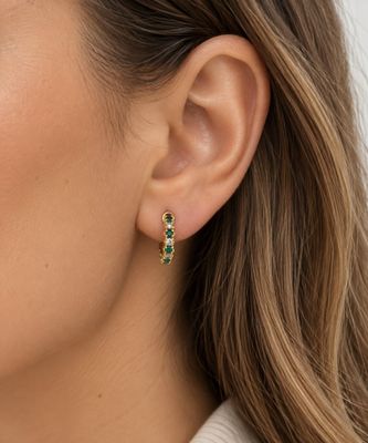 un gros plan sur une femme portant une paire de boucles d'oreilles vertes