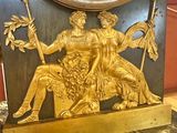 a gold clock with a statue of a man and a woman on it