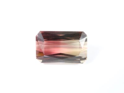 un gros plan d'une tourmaline rose facettée posée sur une surface blanche