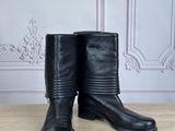black leather boots on a wooden table in front of a wall