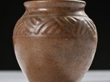 a brown vase sitting on a table with a black background