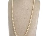a close up of a white pearl necklace on a mannequin
