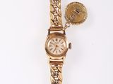 an image of a gold watch and a coin on a white surface