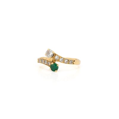 gros plan d'une bague en or avec une pierre verte et des diamants