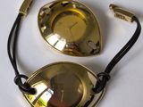 paire de lunettes plaquées laiton, avec un cordon noir sur un fond blanc