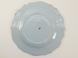 a plate with a blue flower on it on a white table