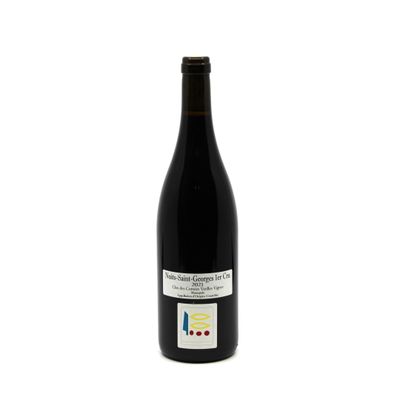 the bottle of red wine is sitting on a white surface